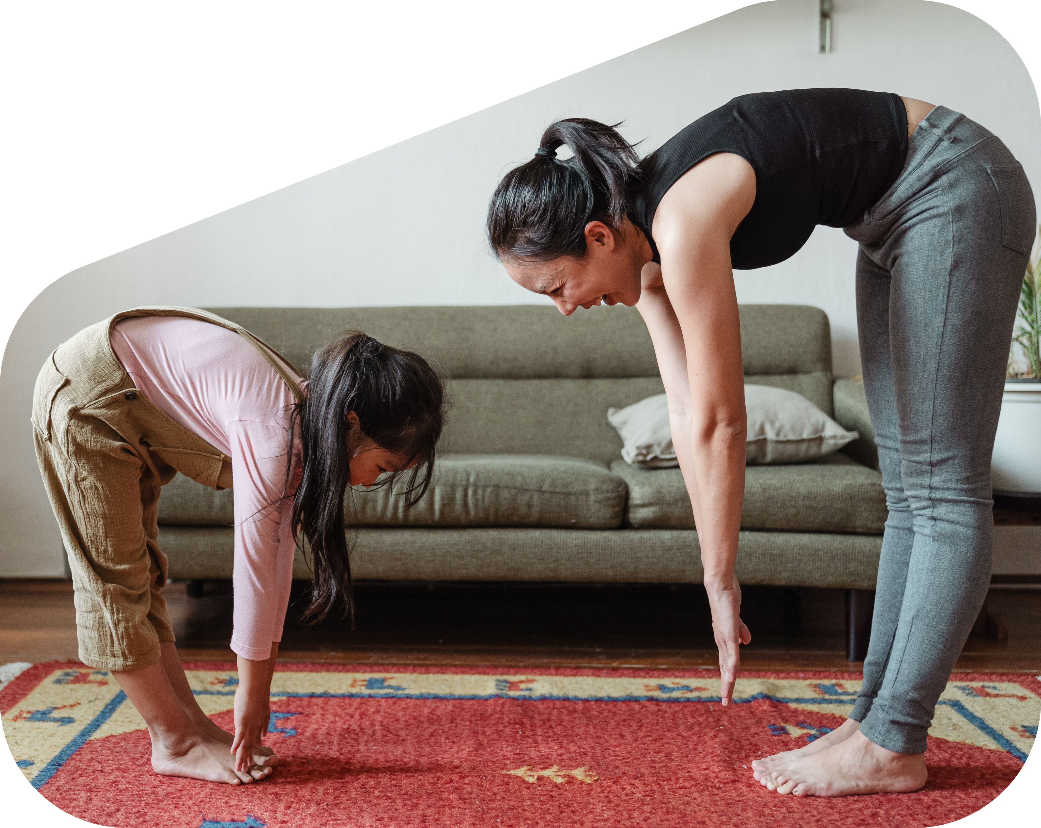 A parent and child stretching side by side during a physical education session at home